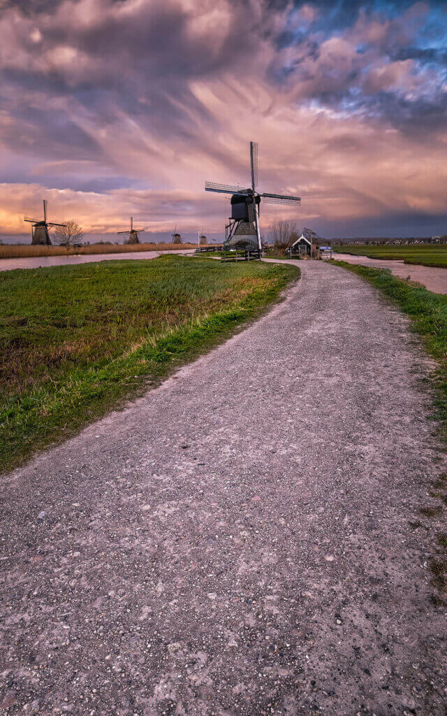 Een kiezelpad naar een molen van Kinderdijk tijdens zonsondergang.