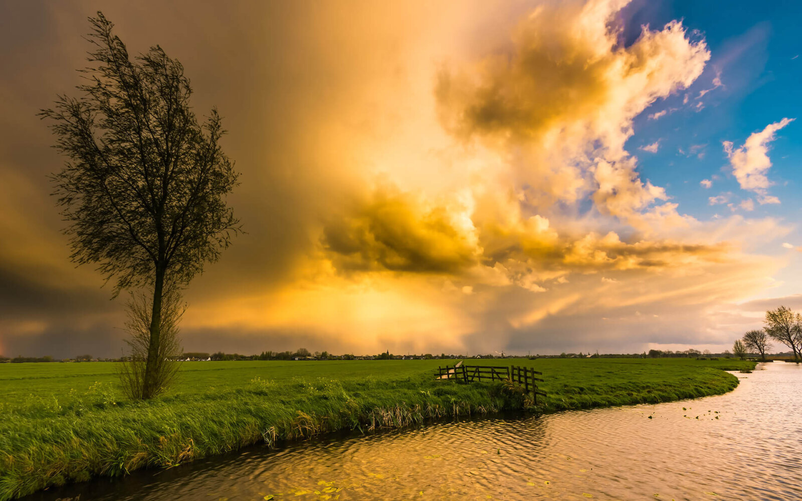 Dreigende regenwolken tijdens zonsondergang boven de Alblasserwaard.
