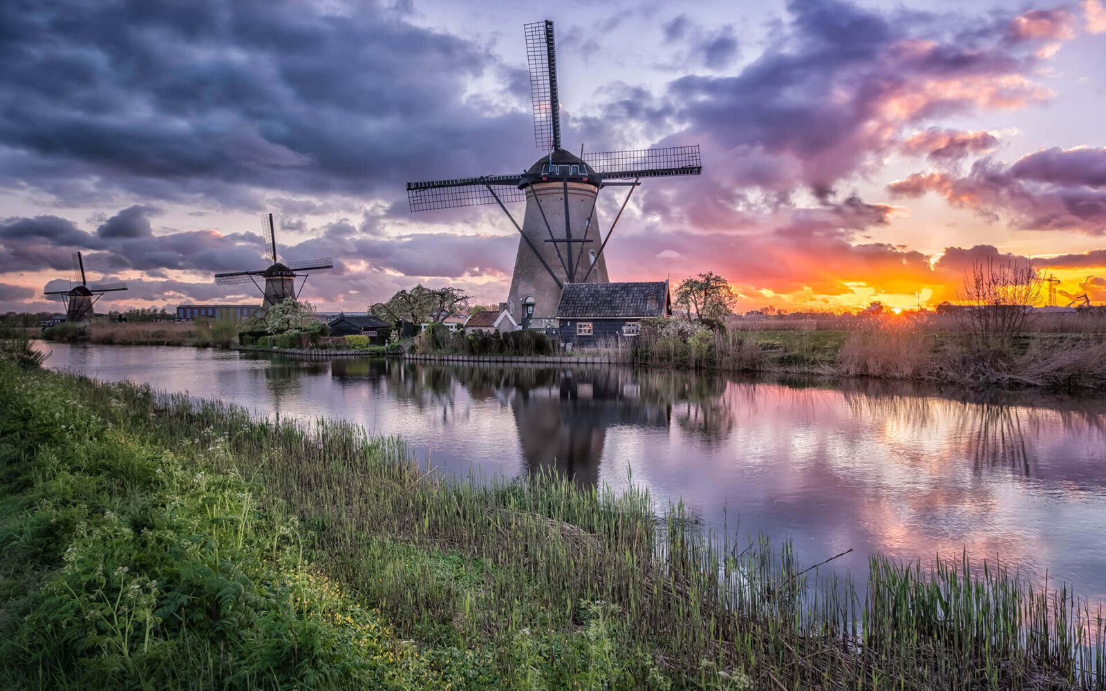 Een zonsondergang met weerspiegeling bij de molens van Kinderdijk.