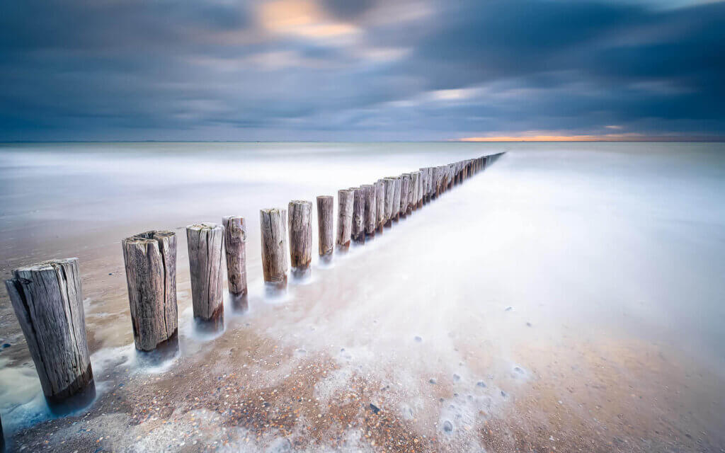 Aan de glazen zee op het strand, met palenrij, bij Dishoek.