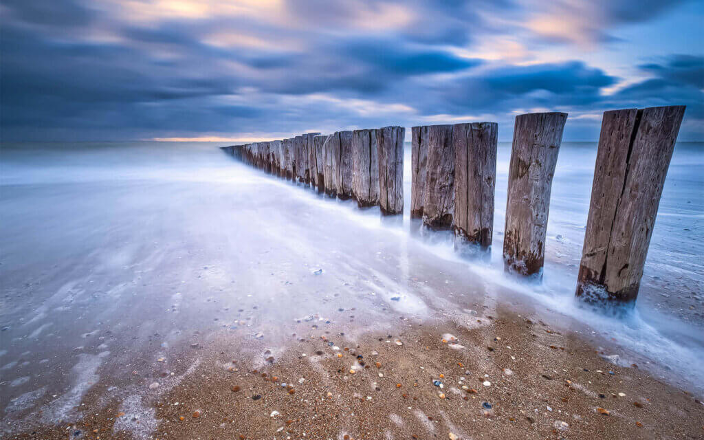 De zee als een spiegeltje bij een palenrij van Dishoek.