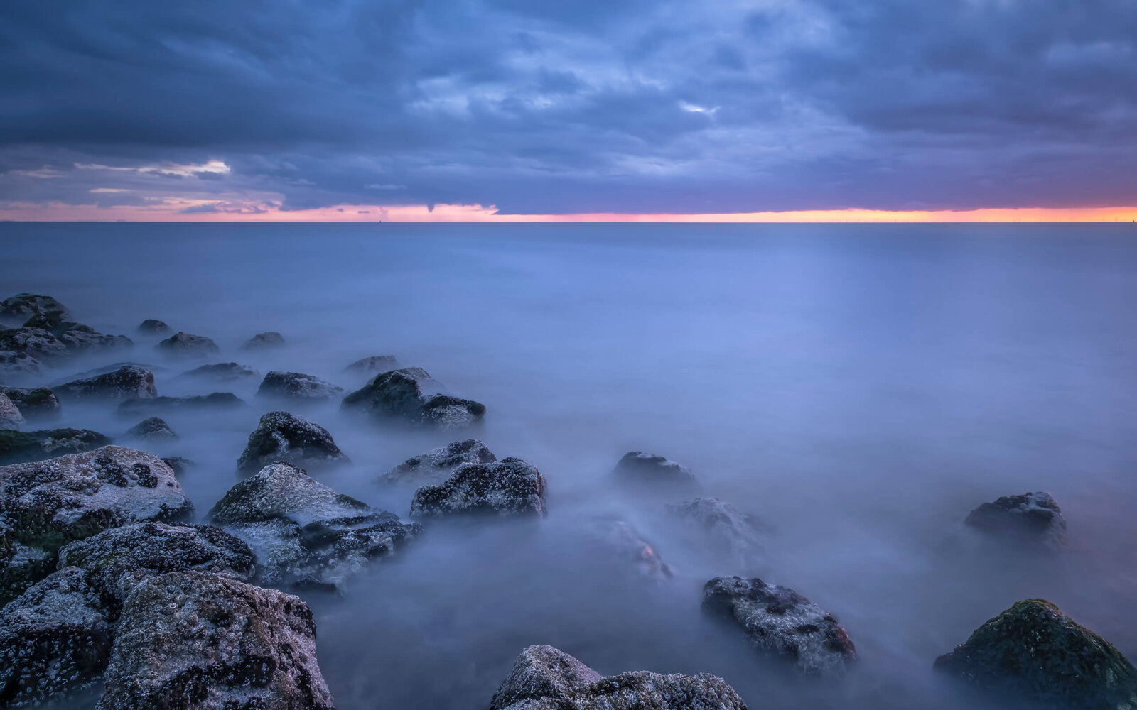 Westkapelle Een serene zonsondergang bij de basaltblokken met zicht op de Noordzee bij Westkapelle.