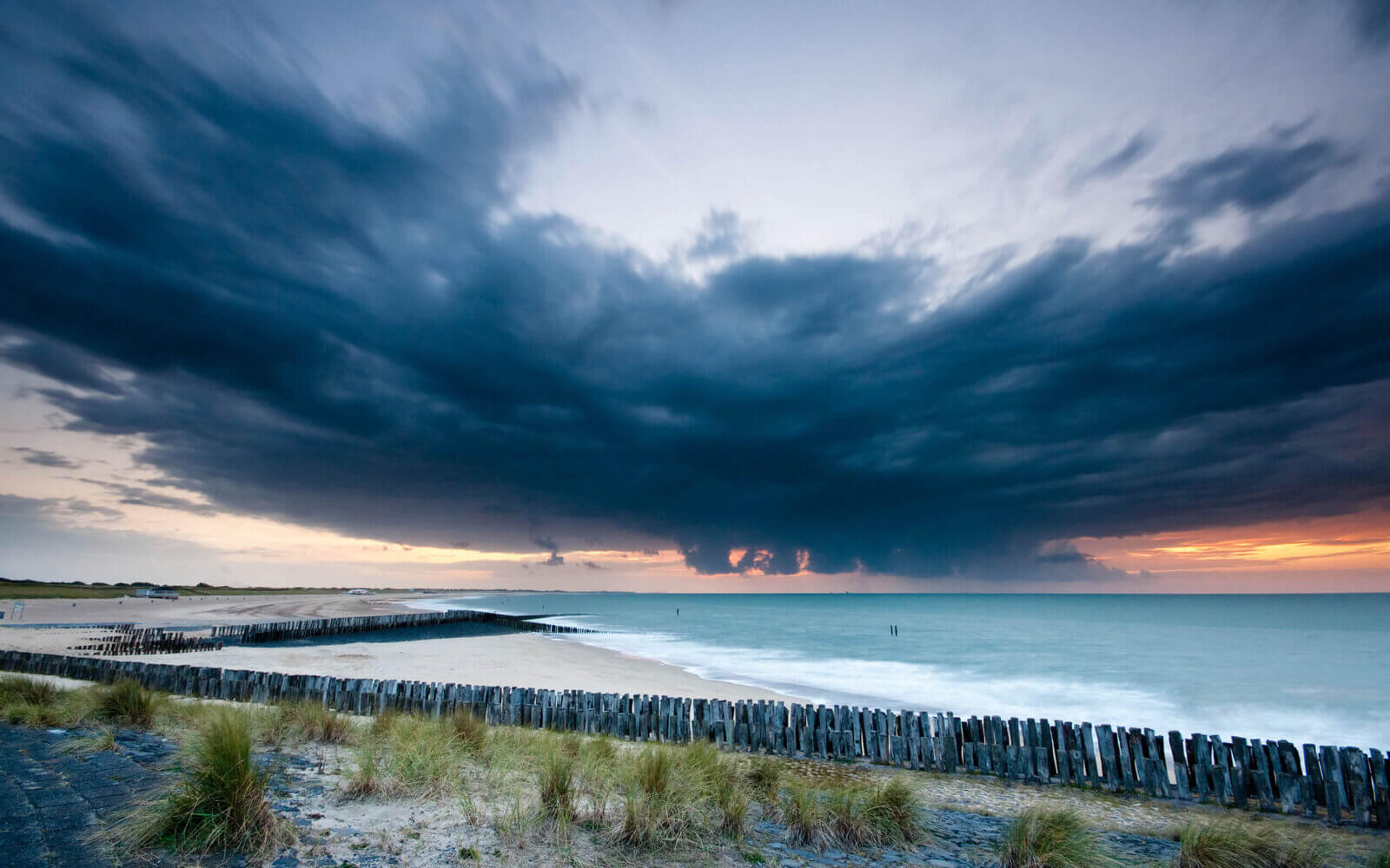 Een donkere regenbui komt dreigend vanaf de Noordzee naar de Zeeuws-Vlaamse kust.