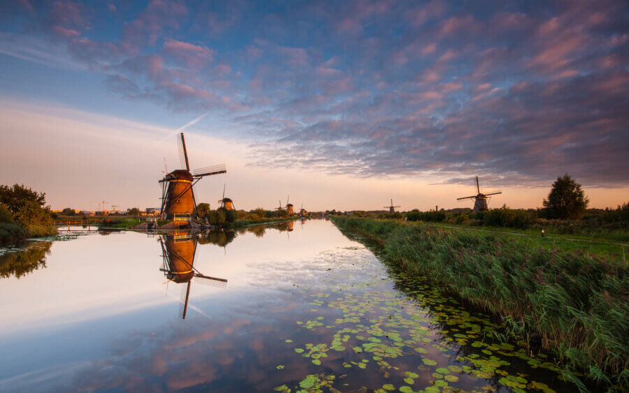 Prachtige zonsondergang bij de molens van Kinderdijk. Het zachte licht wordt weerspiegeld, net zoals de molens.