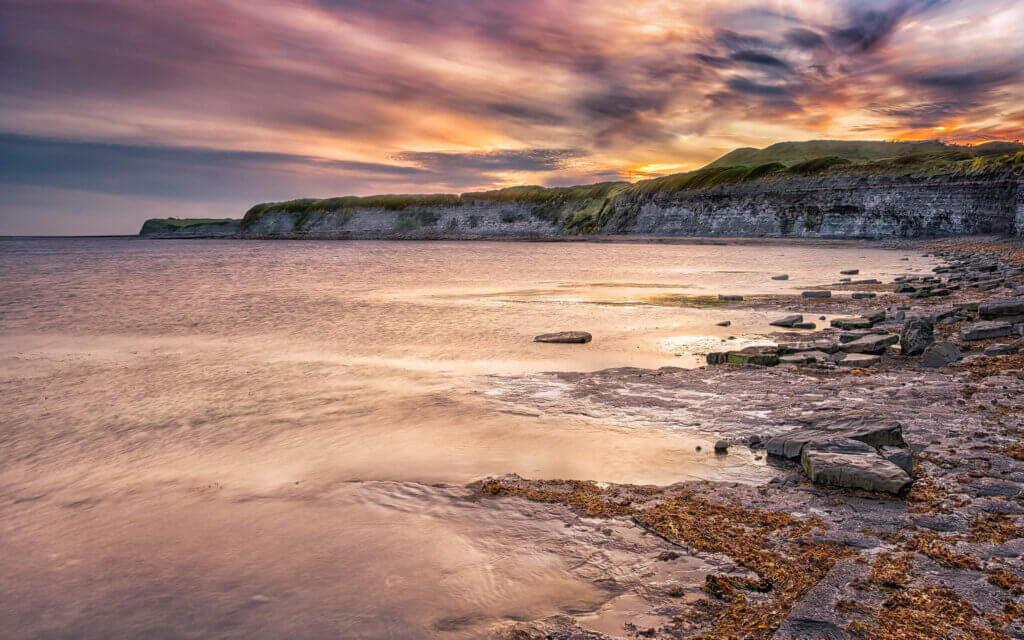 Een zonsondergang aan de Noordzee, in de baai van Kimmeridge Bay in Dorset.