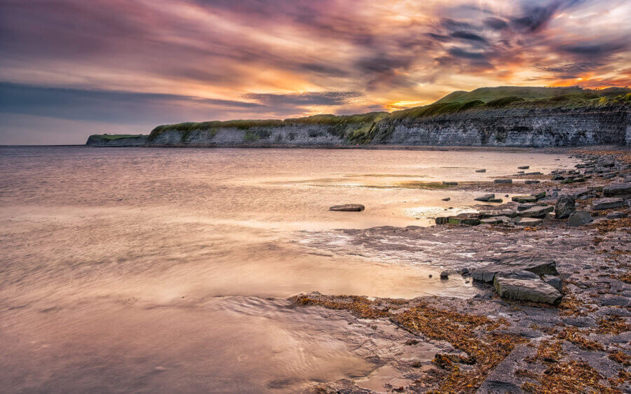 Een zonsondergang aan de Noordzee, in de baai van Kimmeridge Bay in Dorset.