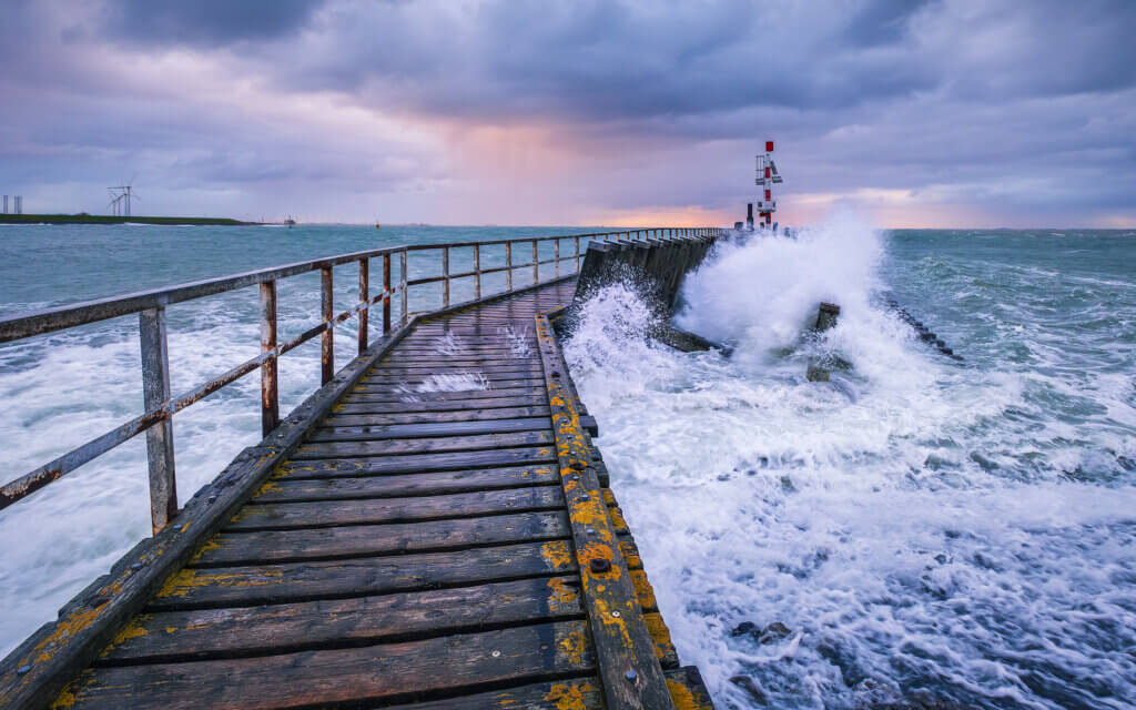 Met windkracht 7 aan de Westerschelde in Vlissingen. De golven breken zich kapot op de steiger tijdens zonsopkomst.