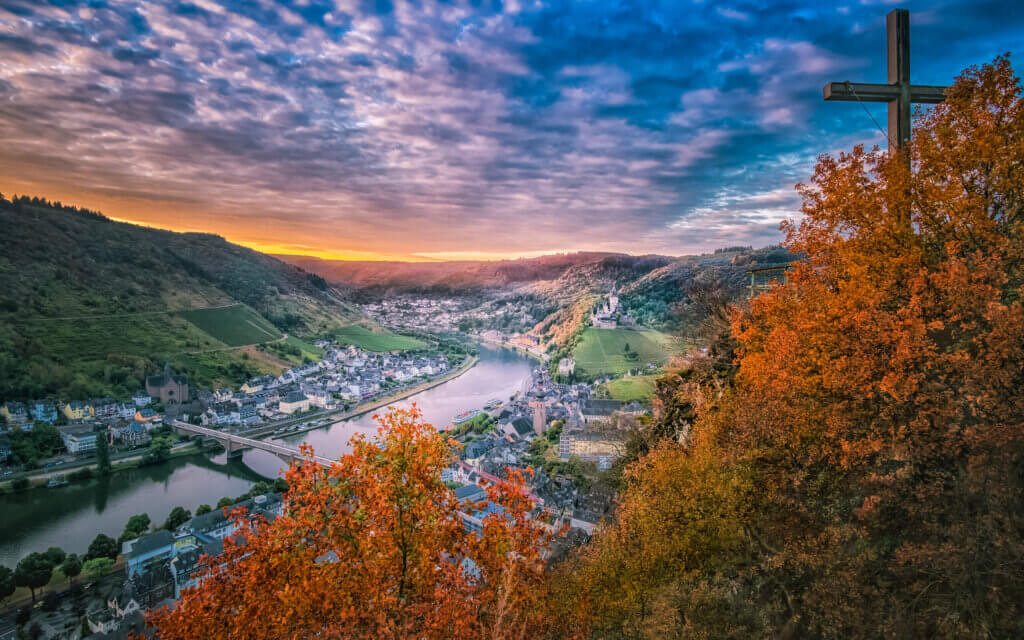 Op een vroege ochtend met zicht vanaf het observatieplatform Pinnerkreuz op de stad Cochem. We zien de Burg Cochem, St. Martin kerk, Skagerak-Brücke en de rivier de Moezel met zonsopkomst.